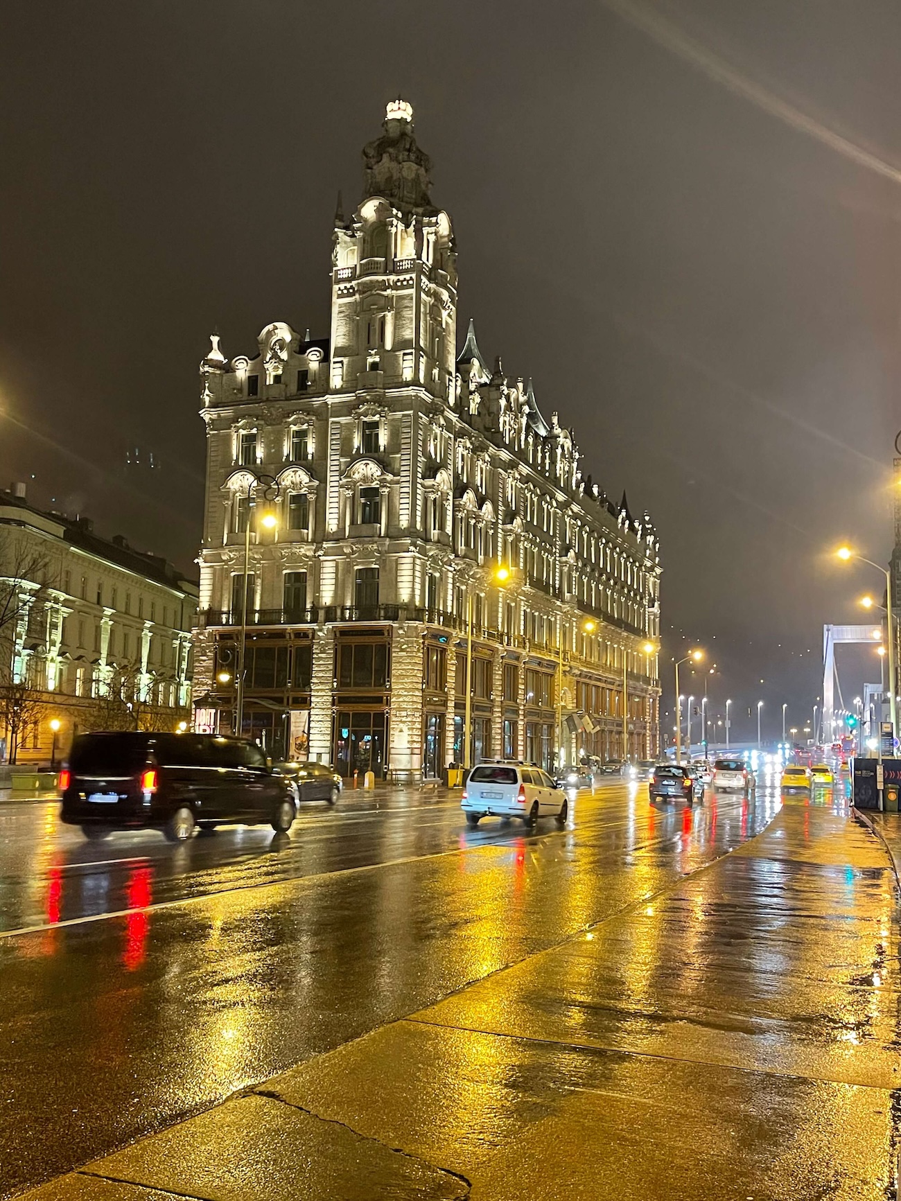 Rain on the streets of Budapest leading up to the glowing Erzsébet Bridge